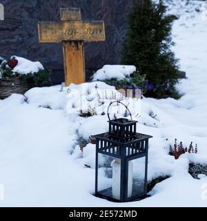 grave light on a snow covered grave withwodden cross in background Stock Photo