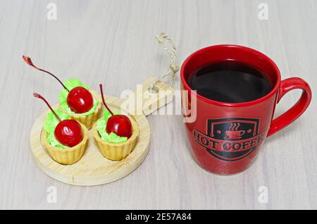 Cherry cakes and a cup of hot coffee on the table Stock Photo