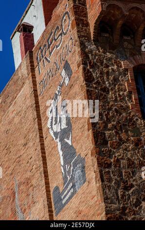 Large stencilled graffito high up on brick wall of building in central Barcelona depicting a man destroying a prison - wording reads Preso Demolicio Stock Photo