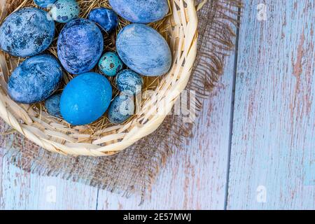 Blue Easter eggs in a natural style. Eggs in a nest of hay in a wicker basket Stock Photo