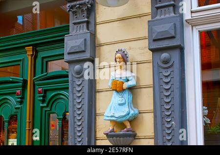 WERNIGERODE, GERMANY - NOVEMBER 23, 2012: The vintage wooden sculpture of beer waitress on the wall of restaurant, located in Breite Strasse, on Novem Stock Photo