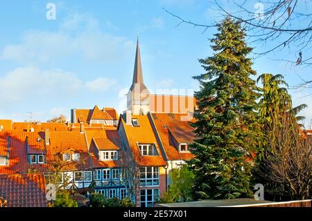 Walk Kehrwiederwall and observe the red tile roofs of half-timbered houses and the tall spire of St Lambert Church, towering the skyline, Hildesheim, Stock Photo