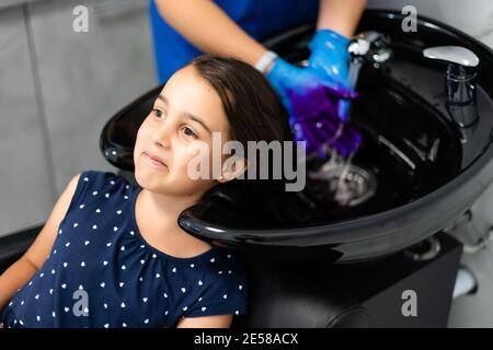 little girl dyes her hair purple in a hairdressing salon Stock Photo