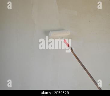 Painter painting white acrylic on house concrete wall with a paint roller Stock Photo