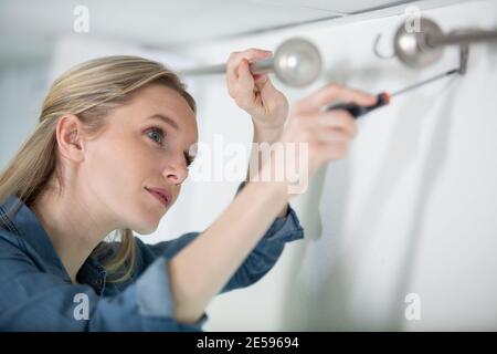 woman installing blinds with screwdriver Stock Photo
