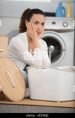 unhappy stressed woman showing signs of fatigue doing laundry Stock Photo