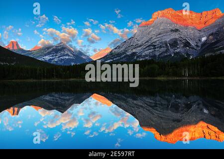 Golden sunrise reflecting off the calm waters of Wedge Pond beneath Mount Kidd in the Kananaskis Country of the Canadian Rockies near Banff National P Stock Photo