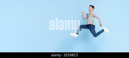 Smiling handsome man jumping in light blue color isolated studio background Stock Photo