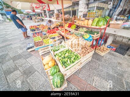 Fruit and vegetables on sale in wooden crates at an outside market next to the quayside alongside Koror Bay in the early morning. Stock Photo