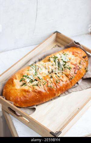 Homemade garlic bread with cheese and herbs on wooden box, light grey background Stock Photo