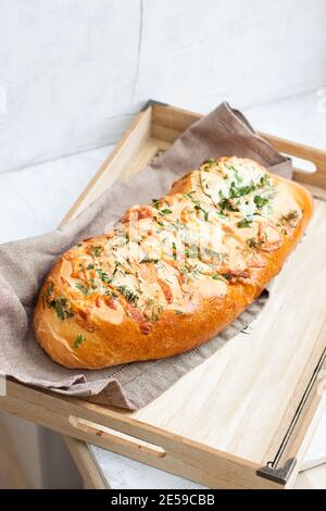 Homemade garlic bread with cheese and herbs on wooden box, light grey background Stock Photo