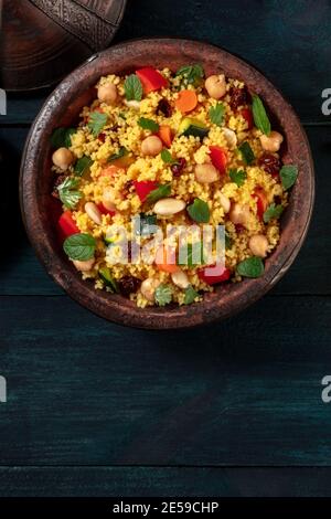 Moroccan couscous closeup in a tagine, shot from above with a place for text on a dark background Stock Photo