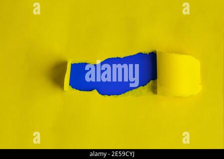 Ripped yellow paper over blue background. Copy space for text. Black space Stock Photo