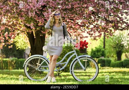 Spring in her basket. retro woman sell tulip flower bouquet. girl under sakura with vintage bicycle. spring beauty and fashion. cherry tree blossom. perfect smell. perfume spa and allergic. travel. Stock Photo