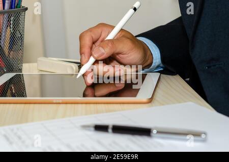 Business men are using a tablet with business documents and pens at  desk. Work from home Stock Photo