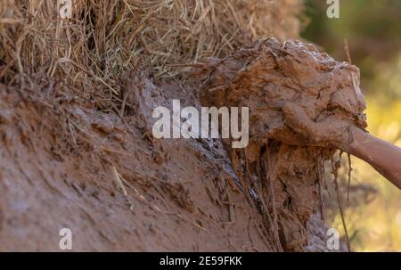 Close-up man's hand holding the clay mixed with dry rice straw to make charcoal kiln. Building traditional charcoal kiln in Thailand. Thai rural. Stock Photo