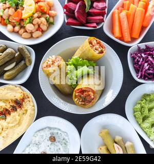 Traditional Turkish and Greek vegetable dinner meze table. with stuffed zucchini, colorful hummus, Cold Appetizers ( with olive oil) in white plates. Stock Photo