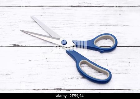 blue handled scissors on a white wooden table Stock Photo