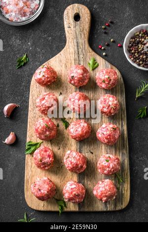 Raw meatballs on black background, top view, copy space. Beef meatballs on wooden board  ready for cook. Stock Photo