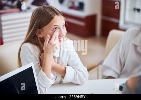 Happy cheerful female child in white shirt wearing contact lens Stock Photo