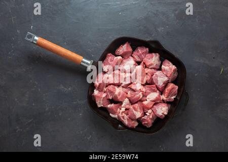 Heap small pieces raw meat in frying pan, top view Stock Photo