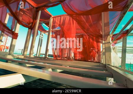 Abstract photographic picture with red sails. Red sails flutter in the wind on white frames on the seashore, copy space Stock Photo