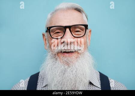 Portrait of hipster senior bearded man wearing glasses with blue desaturaded background Stock Photo