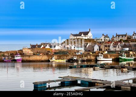 FINDOCHTY MORAY COAST SCOTLAND FISHING BOATS INSIDE THE HARBOUR WHITE CHURCH AND HOUSES ON THE HILL Stock Photo