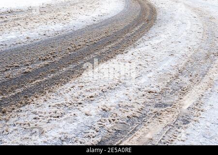 surface of dirty snow-covered slippery road in city on winter day Stock Photo