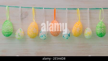 Easter eggs in row hanging on ribbons in springtime. Easter mood, gentle color background. Easter time decoration Stock Photo