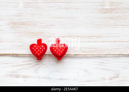 Two sewed red hearts with white polka dots on clothespins over vintage white painted wood background. Valentines background with pair of polka dot hea Stock Photo