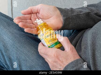 Close up of man person hands holding plastic bottle of Vitamin D tablets pill pills supplement supplements healthcare tablet Stock Photo