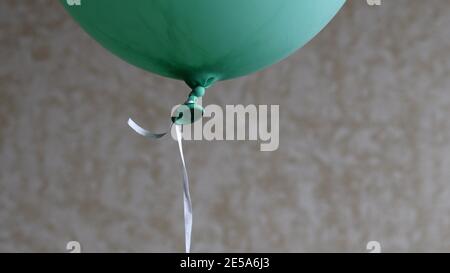 Soft focus to bottom part of green balloon with rubber tail tied