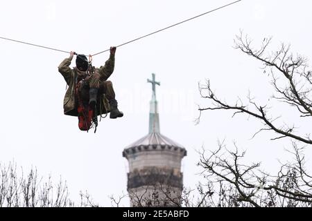 HS2 Rebellion protester on a zip line between two trees in an encampment in Euston Square Gardens in central London, where the protesters have built a 100ft tunnel network, which they are ready to occupy, after claiming the garden is at risk from the HS2 line development. The spire of St Pancras New Church is in the background. Picture date: Wednesday January 27, 2021. Stock Photo