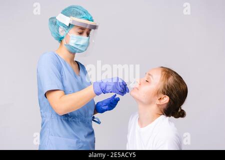 A healthcare professional wearing a protective suit and disposable sterile gloves takes samples from a patient's nose for a covid 19 test. Pandemic Stock Photo
