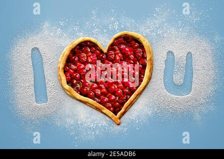 Simple composition for valentine's day or any romantic celebration with the message, I love you, written with a heart shape cherry pie and flour on a Stock Photo