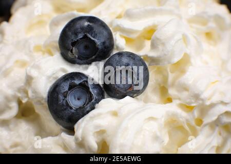 Fresh blueberries in a whipped cream close up. Blueberry in a cream in macro. Fruit salad. Fruit vitamin.  Stock Photo