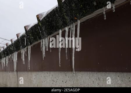 The snow on the roof melts and forms ice icicles. Stock Photo