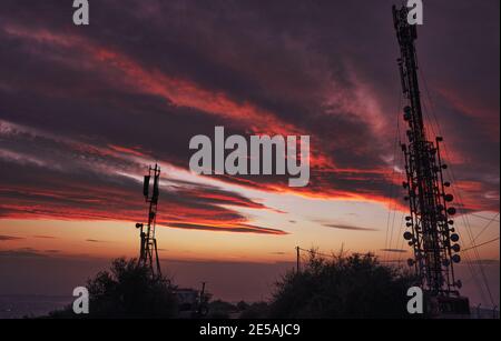 Extraordinary clouds on fire over the antenna after the sunset in Attiki, Greece Stock Photo