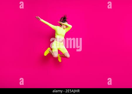 Full length body size photo of jumping young girl wearing yellow sportswear showing hype isolated on bright pink color background Stock Photo