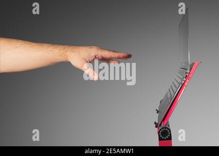 Open slim and modern laptop computer at a red stand isolated at gradient grey background and trying to touch it a male hand, with copy space, details, Stock Photo