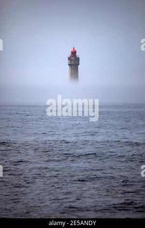 The dramatic La Jument lighthouse, shrounded in summer fog, off the coast of the Ile d'Ouessant, Brittany. The iconic 47-metre high lighthouse was bui