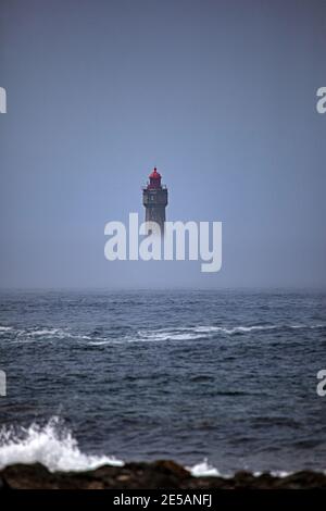 The dramatic La Jument lighthouse, shrounded in summer fog, off the coast of the Ile d'Ouessant, Brittany. The iconic 47-metre high lighthouse was bui