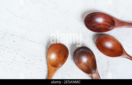 Small spoons made of dark wood, on white working board, view from above, space for text left side Stock Photo