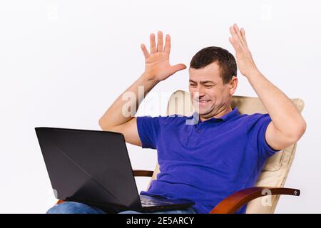A deaf man with a laptop raised both hands up in a gesture indicating that he is happy. Video communication in live on social networks using non Stock Photo