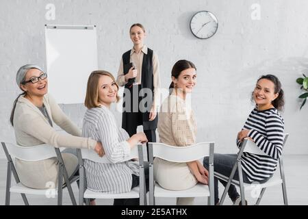 happy interracial businesswomen and cheerful speaker smiling during lecture Stock Photo