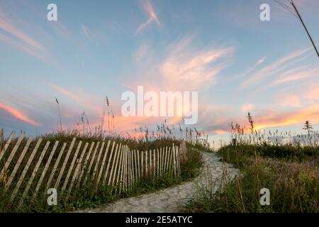 Sunset creates cotton candy skies over the sand dunes at Atlantic Beach, North Carolina. Sea oats sway in the breeze along the path that leads to the