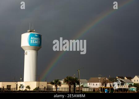A rainbow glows in the sunshine after a storm passed through  Atlantic Beach, North Carolina. A faint double rainbow can be seen. Stock Photo