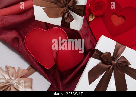 Valentines day background, composition of gift boxes and red heart metal shaped boxes, with bows and ribbons, top view on damask fabric. Useful for gr Stock Photo