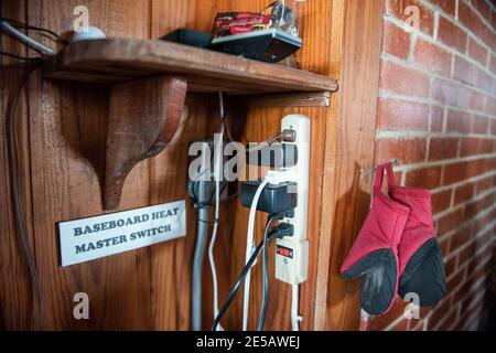 A surge protector with many cords plugged in is mounted on the wall. Stock Photo